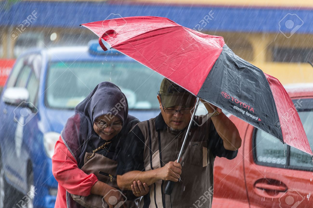 -August-10-2014-Couple-of-people-sheltering-under-umbrella-while-raining-in-the-stre-Stock-Photo.jpg